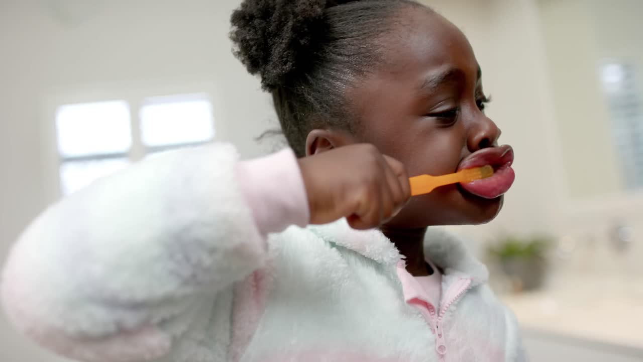African american girl brushing teeth in bathroom, slow motion