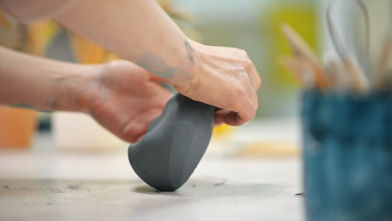 The master of sculpting pottery working in a studio. Kneading a piece of clay with her hands. Tools on the table. Slow motion