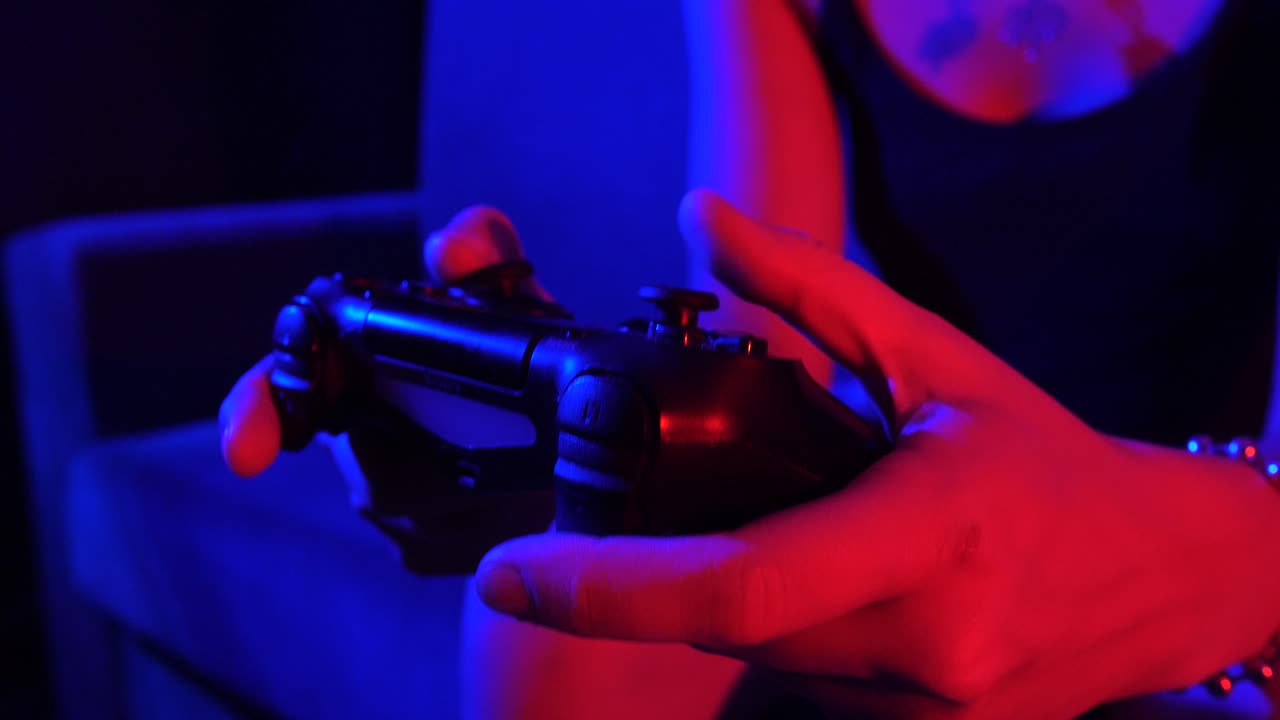 Gamer's Hands Playing with Controller in Red and Blue Neon Light