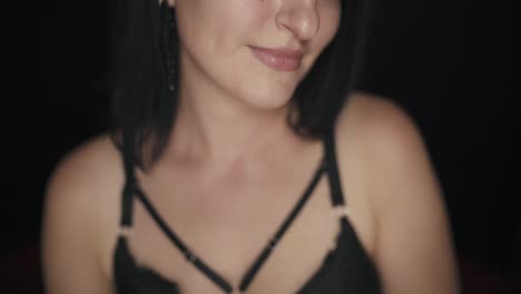 close up of a pretty brunette woman doing a kissing gesture and smiling on black background