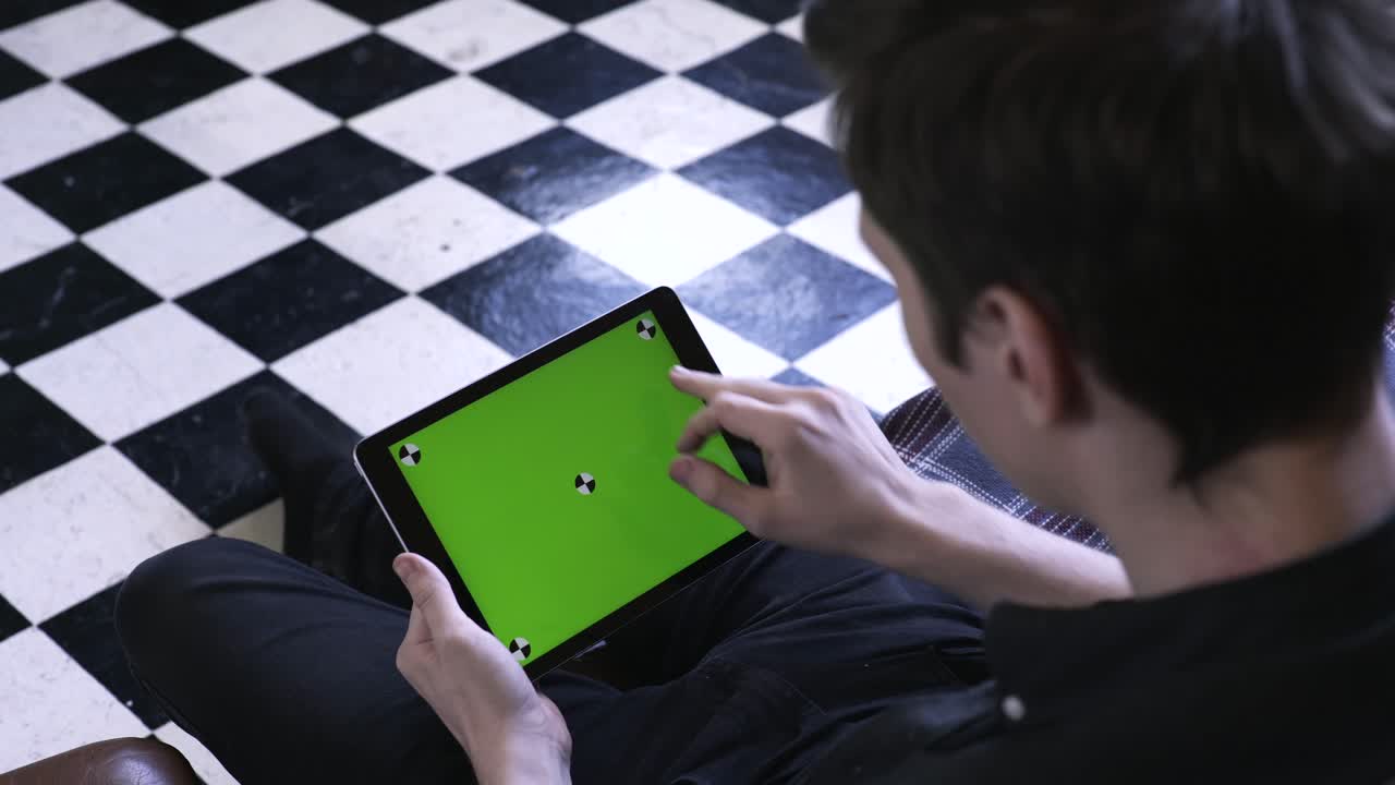 녹색 화면을 가진 태블릿을 사용하는 사람