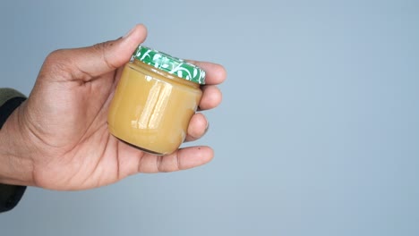 hand holding a small jar of baby food
