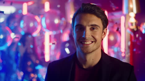 hot man biting lip at party. guy staring at lens on neon lights background