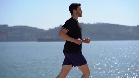 handsome young sportsman running at riverside