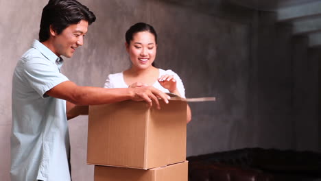 young asian couple unpacking moving boxes