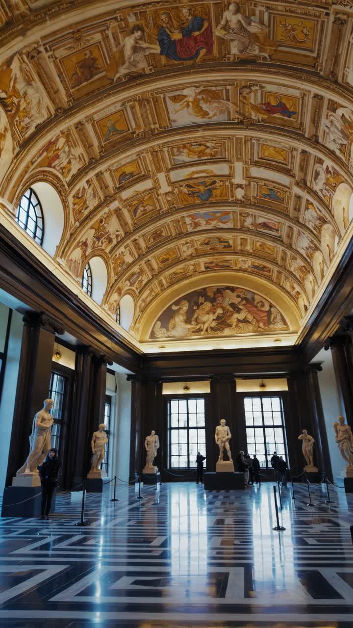 Wide-angle video shot of a grand hall with ornate vaulted ceilings and classical statues