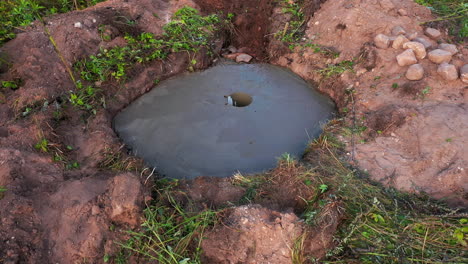 base de cemento colocada para ahumadero, trabajador cavando hoyo para tubería con pala