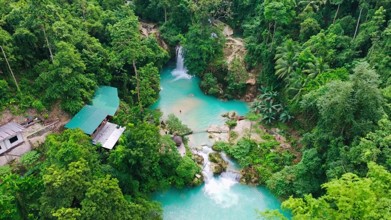Una vista aerea rivela vivaci cascate turchesi in mezzo a una fitta foresta pluviale a Cebu