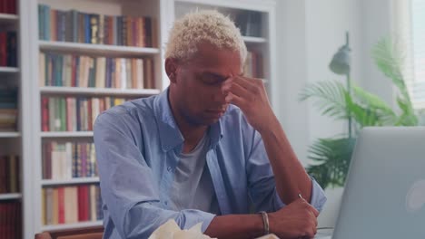 young african american man sits in office with eyes closed is stressed