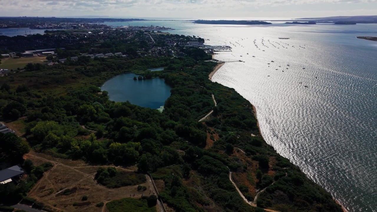 Riprese aeree che mostrano una laguna costiera riparata e una costa boscosa vicino al porto di Poole nel Dorset, Inghilterra. Ormeggi per barche, aree residenziali e l'ampio porto naturale