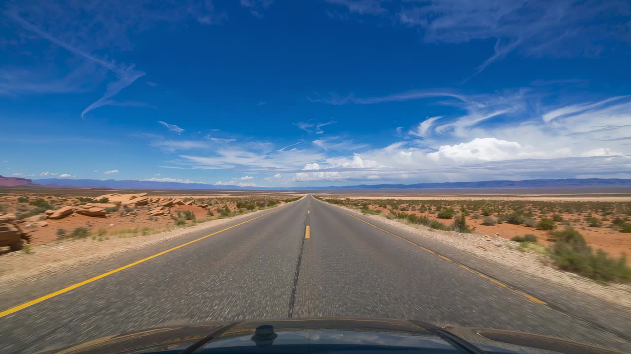 Motor revolucionado, cámara enfocando una larga carretera desértica hacia el horizonte, mostrando el capó y la línea amarilla
