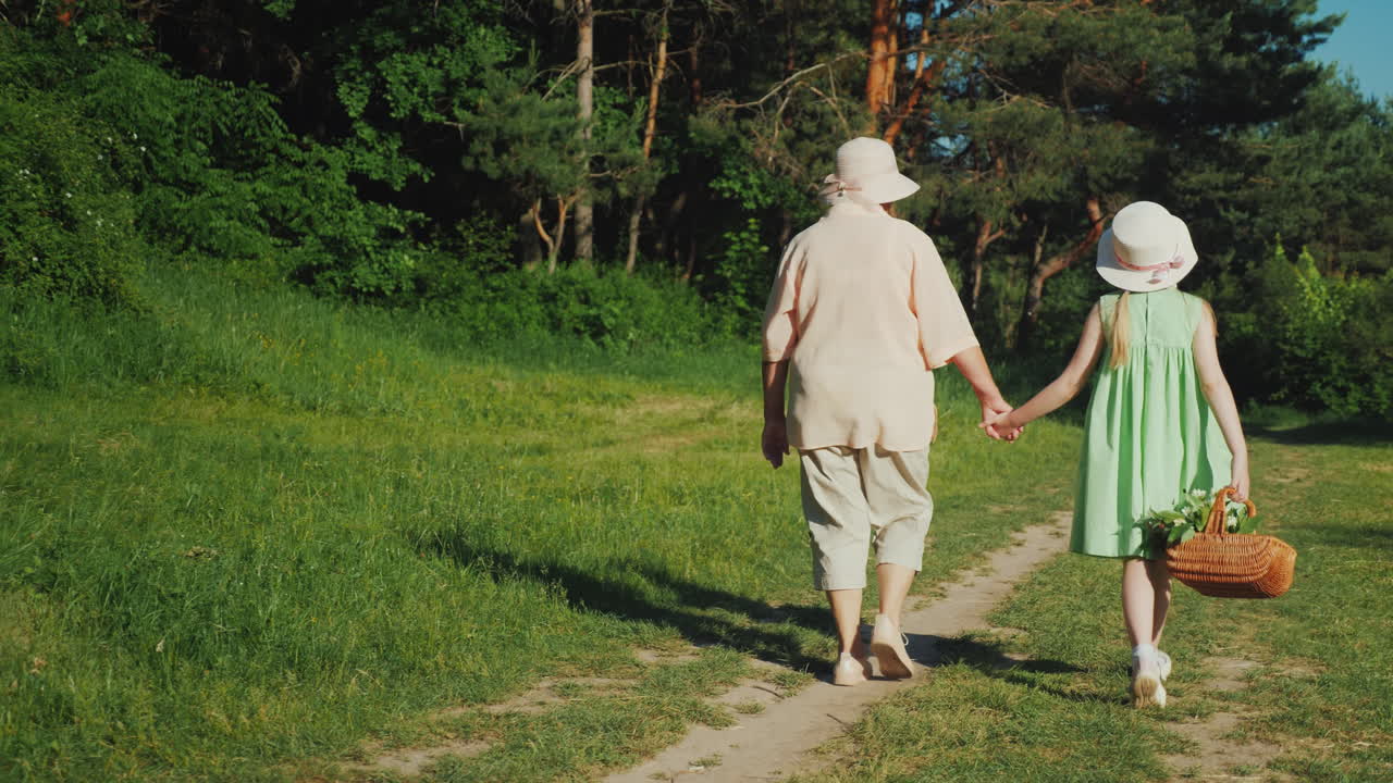 할머니는 바구니를 들고 손을 잡고 숲에서 손녀와 함께 걷고 있다
