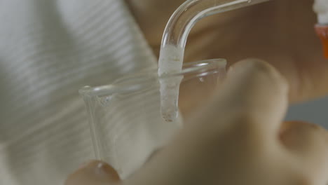 close-up of a clear liquid gently being drawn from a burette into a test tube in a laboratory setting.