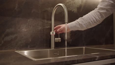 tracking shot of hand activating point of use hot water faucet