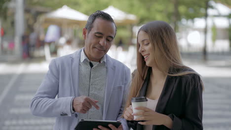 male and female colleagues using tablet pc outdoor