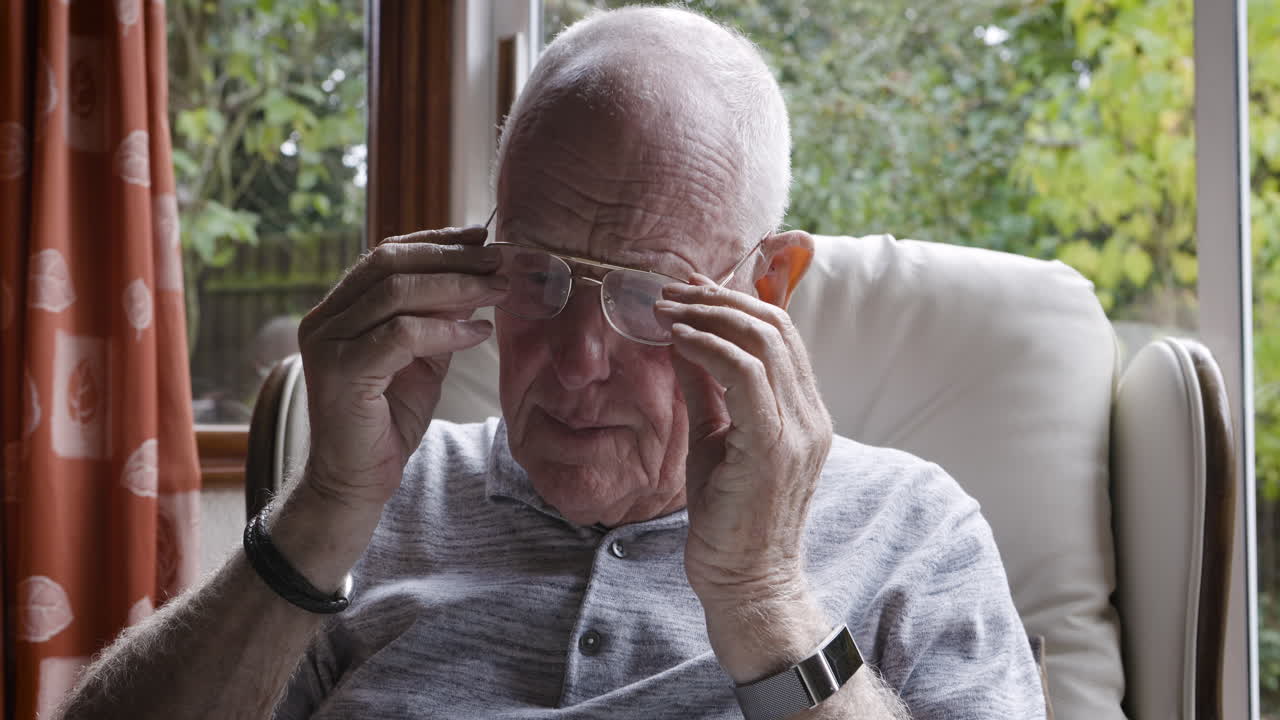 An elderly man sitting in a chair near a window