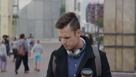 portrait attractive young businessman drinking coffee using smartphone checking messages tedxting on mobile phone enjoying relaxed urban lifestyle