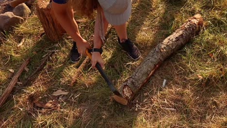 male scout cutting wood with axe, teen unrecognizable, static