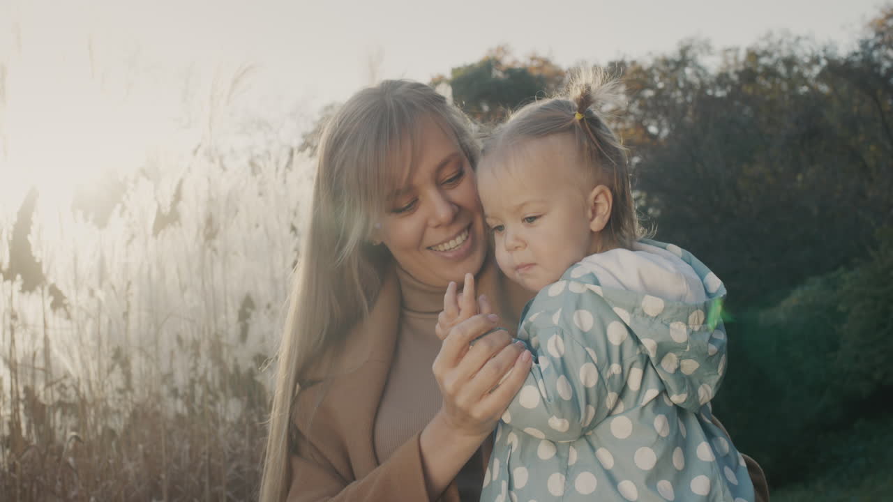 retrato de una madre joven feliz con su pequeña hija. juntos en un paseo por el parque de otoño