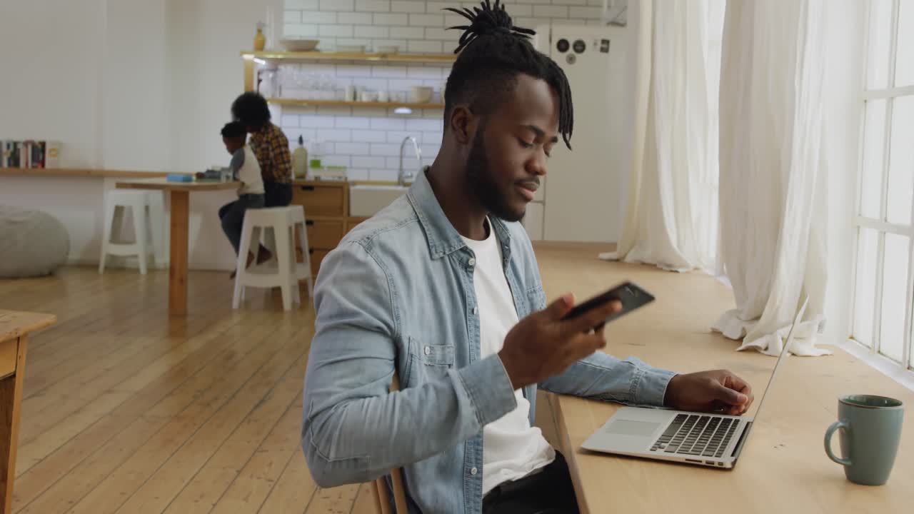 Man using smartphone and laptop at home