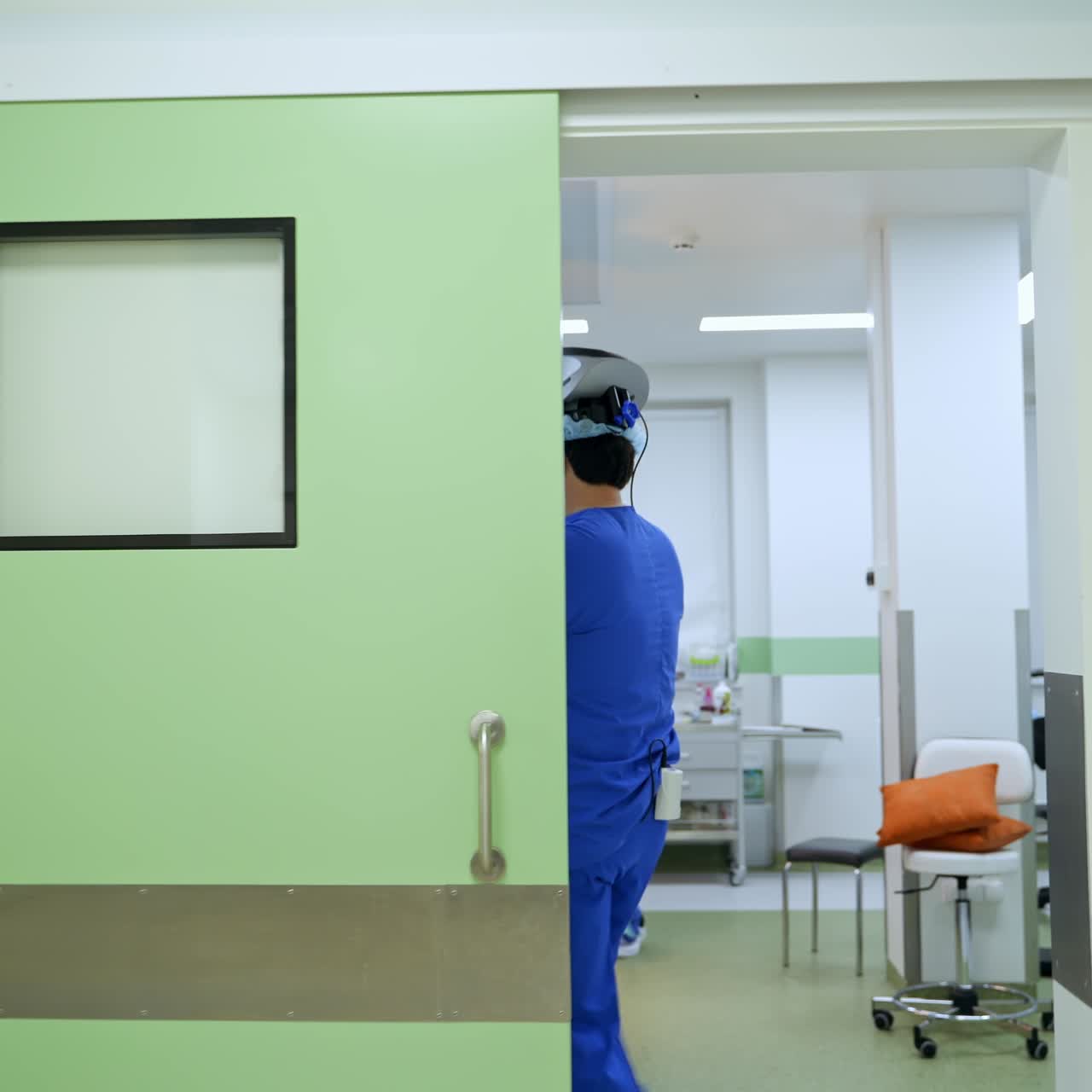 Um cirurgião aplica antisséptico nas mãos, usando um capacete tecnológico. Um especialista entra na sala de cirurgia