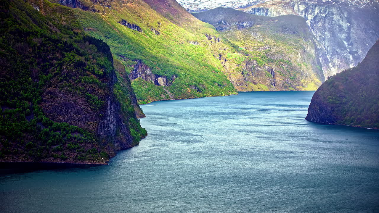 Statische Aufnahme von Motorbooten, die den Lovatnet See im Zeitraffer passieren, entlang eines wunderschönen Fjords in Norwegen, umgeben von einer Bergkette