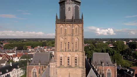 primer plano de la torre de la catedral de walburgiskerk oscureciendo el barco de la iglesia y la torre de entrada de la muralla de la ciudad medieval de drogenapstoren en el fondo