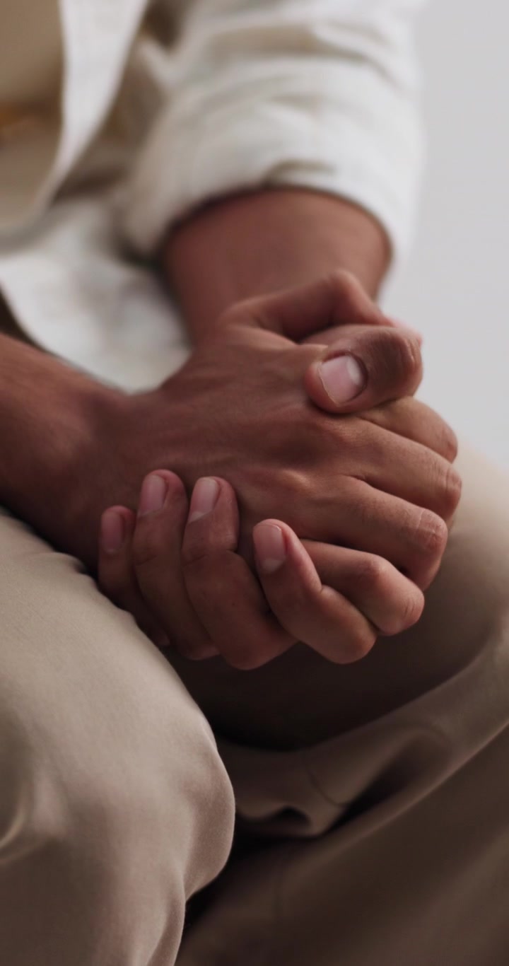 Primo piano di una persona che intreccia le mani in un gesto pensieroso