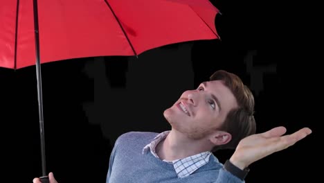 hombre sonriente bajo un paraguas rojo comprobando la lluvia con la mano extendida, sobre un fondo negro