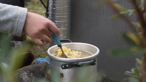 woman stirring and cooking rotini pasta on a casserole. - close up