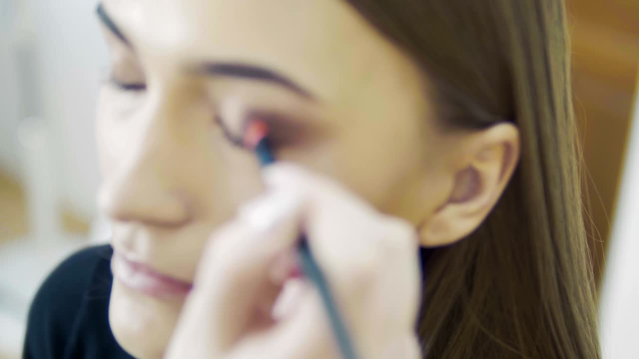 el estilista de maquillaje hace el efecto de los ojos de humo para el modelo en la sesión de fotos