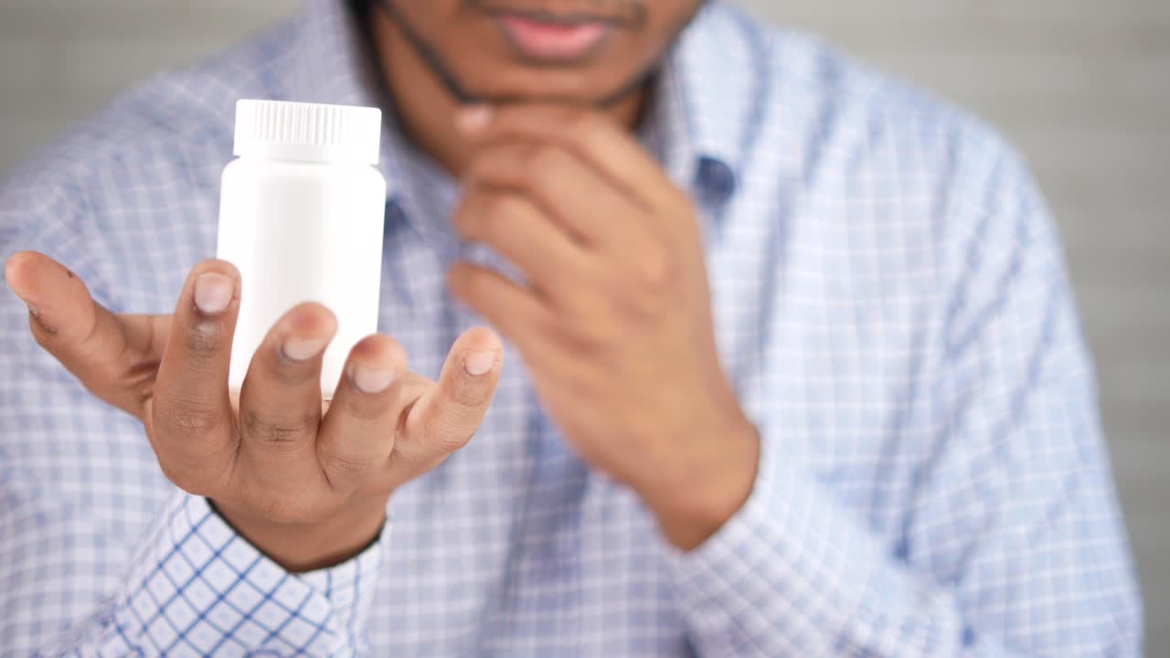 persona que sostiene un frasco de medicamento blanco