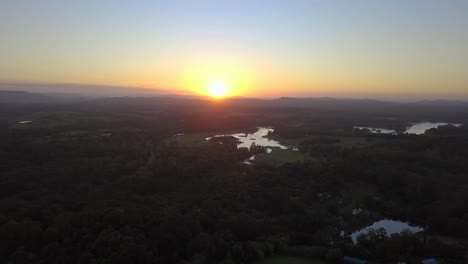 fast aerial view of sunshine coast landscape with forests, lakes, mountain and beautiful sunset