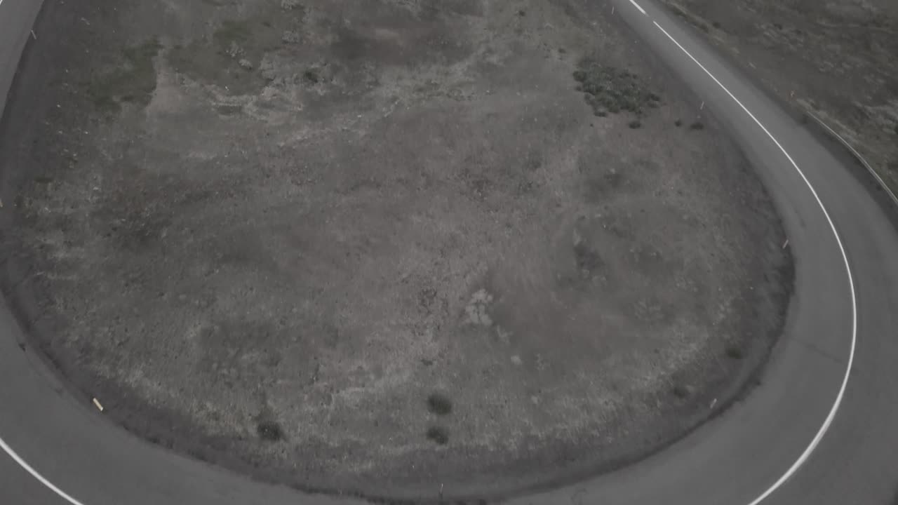 아이슬란드의 안개가 자욱하고 극적인 풍경 속에서 구불구불한 도로를 타고 내려가는 스케이터의 드론 샷