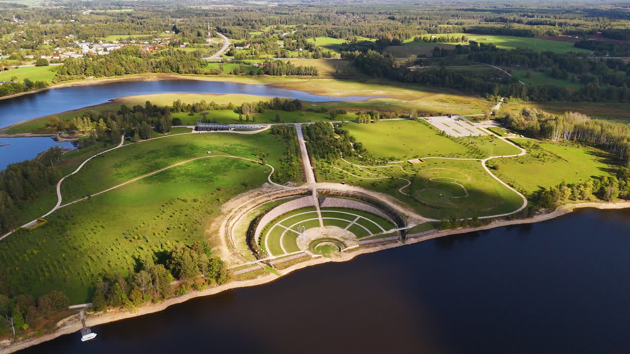 Eine Luftaufnahme eines atemberaubenden grünen Parks mit einem kreisförmigen Amphitheater am Wasser. Die Kokneses pilsdrupas sind Burgruinen in Koknese, Lettland.