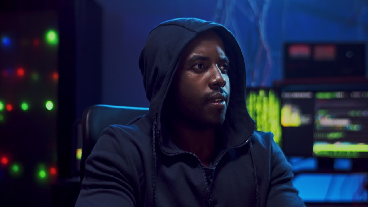 närbild av den unga, glada hackaren som skapar virus i det mörka rummet på natten och ler