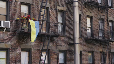 The-Ukrainian-flag-waving-in-the-wind-for-solidarity-on-a-house-in-Manhattan,-static-shot