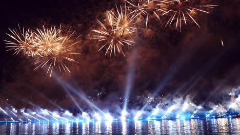 fuegos artificiales coloridos festivos e iluminación en el cielo oscuro con un hermoso reflejo en el agua. velas escarlata de vacaciones