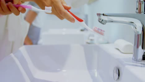 chica lavando su cepillo de dientes en el fregadero 4k