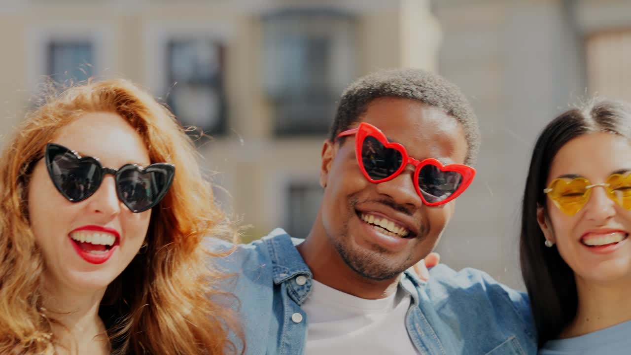 A happy diverse group of friends wearing heart-shaped sunglasses laughing outdoors