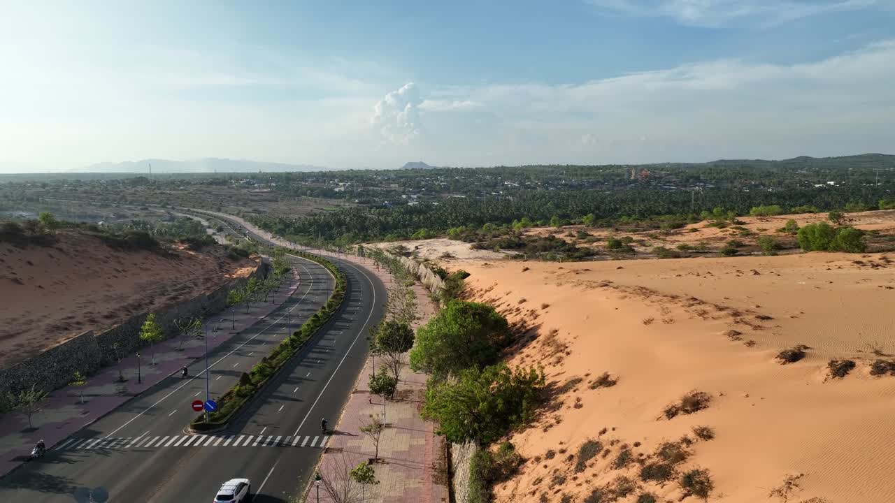 drone shot captura vehículos moviéndose a lo largo de la carretera sinuando a través de las dunas de arena, vasto paisaje árido se extiende sin fin, mezclando las dunas lisas con la tierra en texas, ee.uu.