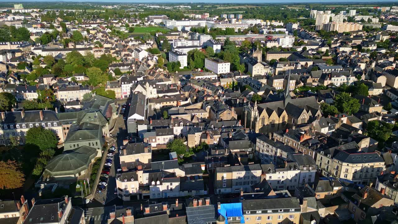 Église Saint-Vénérand and surrounding cityscape on sunny day, for travel or architectural content, Laval, France. Aerial drone forward