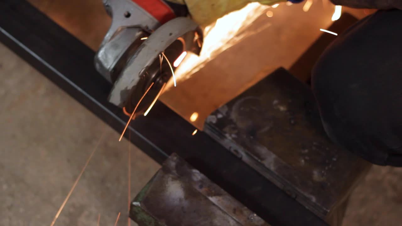 Hand worker cutting piece of black square metal bar, close high angle