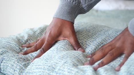 persona ajustando una almohada en una cama
