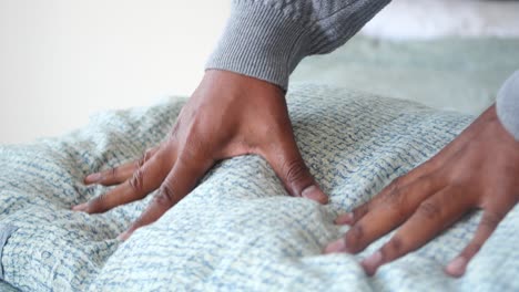 person adjusting a pillow on a bed