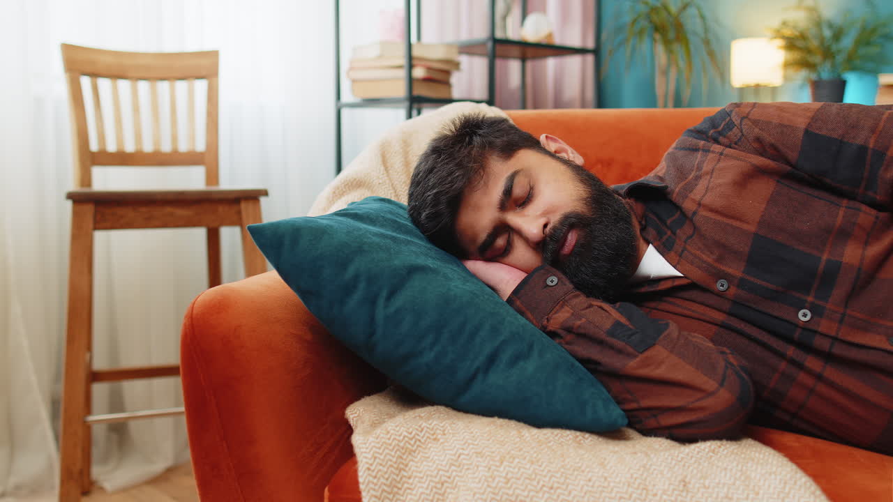 joven indio cansado acostado en la cama tomando un descanso en casa durmiendo durmiendo en el sofá