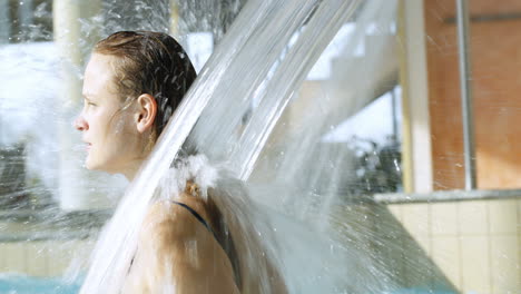 Frau-Genießt-Starke-Wasserdusche-Im-Pool