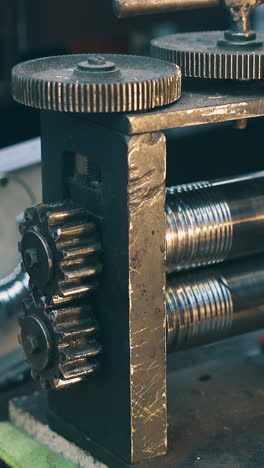 cu shot: skilled jeweler processes long metal silver wire with forge-rolling machine tool at workplace in workshop closeup