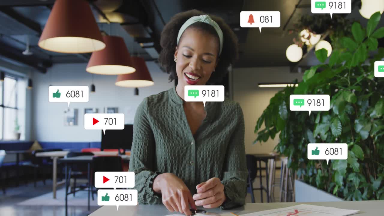 animación de iconos de redes sociales sobre una mujer afroamericana haciendo una videollamada en la oficina