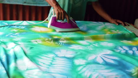 Learning-homemade-batik,sarong,-pareo,-Dark-skin-man-ironing-dried-paint-to-seal-Mahe-Seychelles-25fps-8